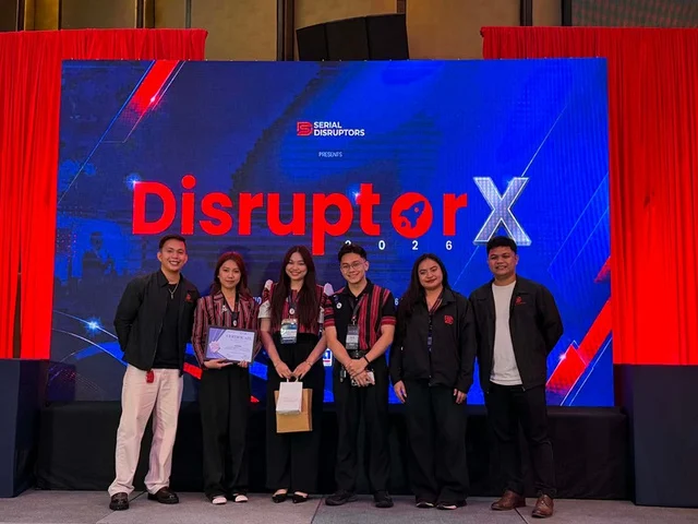Six people standing in front of a large DisruptorX 2026 screen.